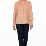 Blusa elegante color melocotón para mujer con cuello fruncido y manga larga combinada con pantalón oscuro.