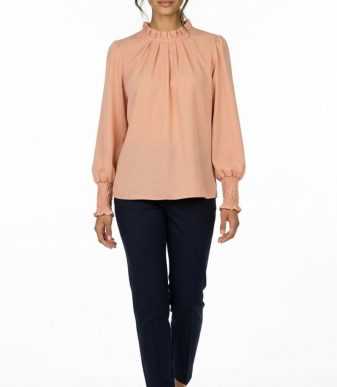 Blusa elegante color melocotón para mujer con cuello fruncido y manga larga combinada con pantalón oscuro.