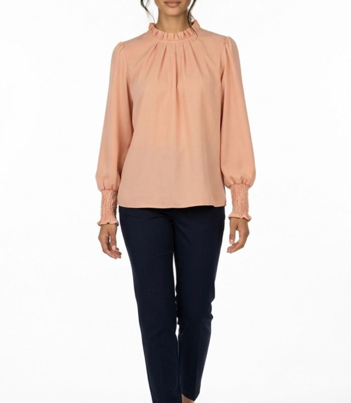 Blusa elegante color melocotón para mujer con cuello fruncido y manga larga combinada con pantalón oscuro.