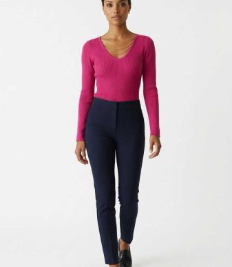 Jersey de punto fucsia ajustado para mujer con escote en pico y manga larga combinado con pantalón oscuro.