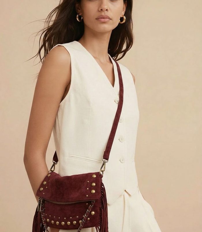 Bolso bandolera burdeos para mujer con flecos y tachuelas metálicas, estilo boho chic con asa larga ajustable.