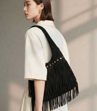 Bolso negro de mujer con flecos largos y tachuelas doradas, estilo boho chic para llevar al hombro.